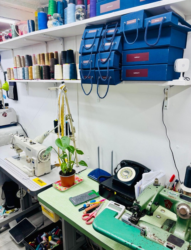 Sewing workshop with industrial machines and wall shelves of colourful thread spools